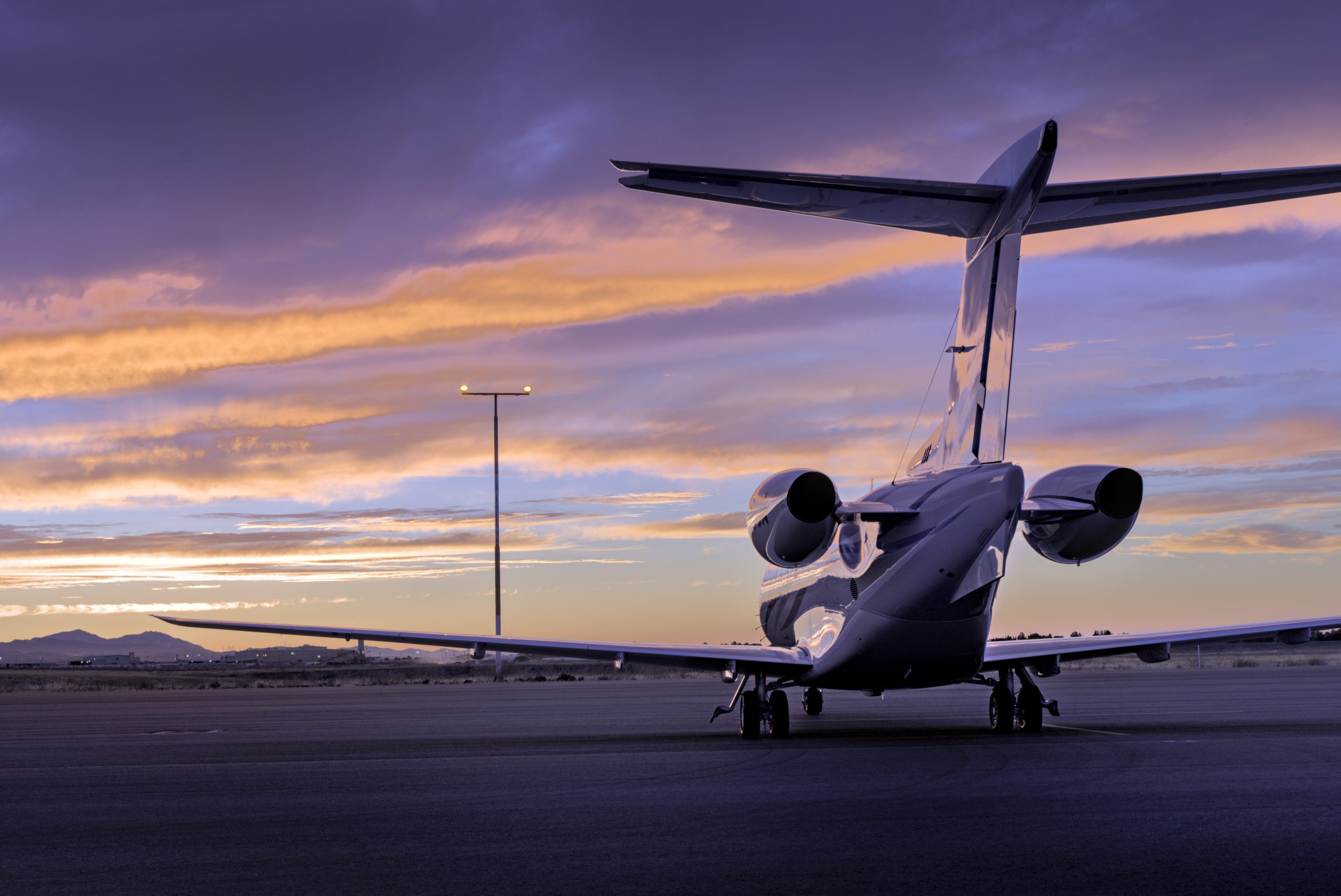 Rear view of a private jet beneath a purple and gold sunset — photo by Kim R. Hunter